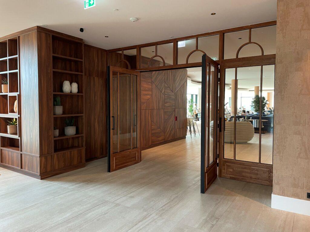 Premium custom joinery featuring architectural wood paneling, bespoke shelving, timber-framed glass doors, and luxury interior finishes by SAMA TEAM.